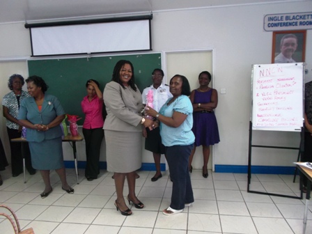 President of the Nevis National Women’s Council Ms. S. Patricia Claxton receives a token from Assistant Secretary in the Ministry of Social Development Ms. Michelle Liburd while other members of the Council look on